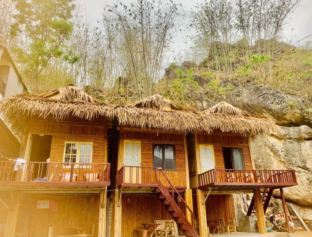 dom z dachem krytym strzechą i balkonem w obiekcie Green homestay Mai chau w mieście Mai Châu
