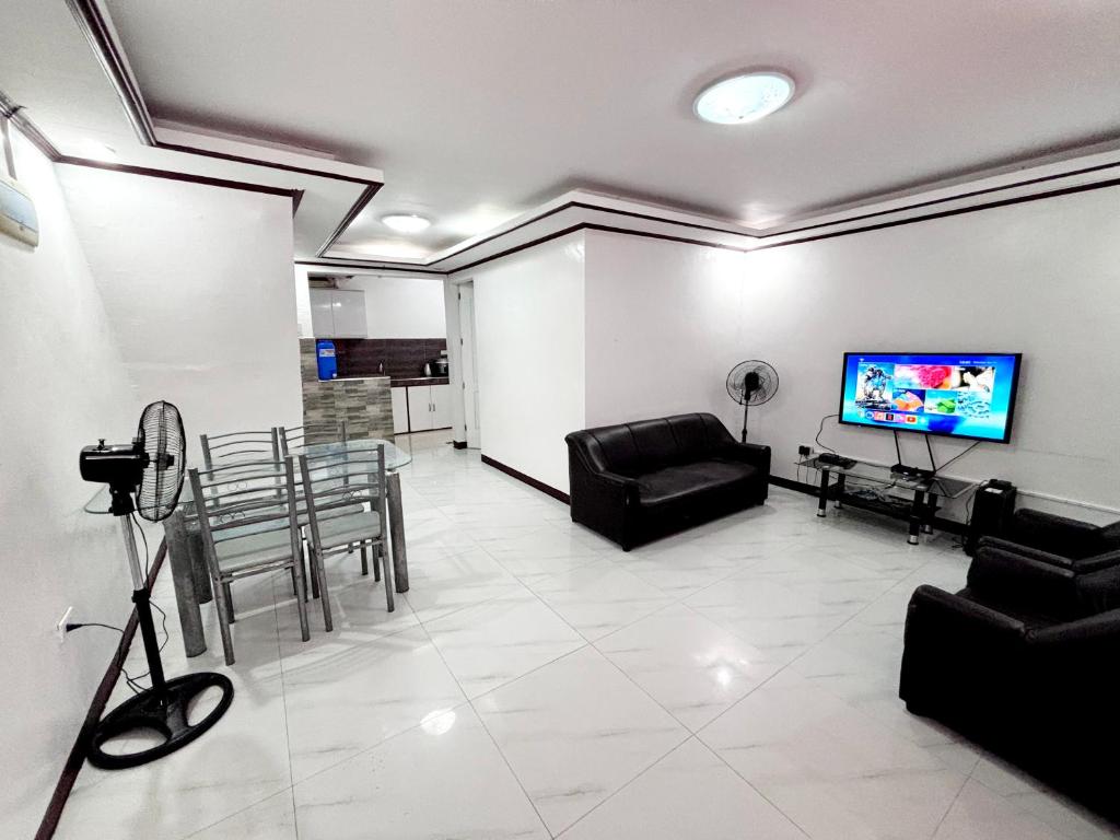 uma sala de estar com uma televisão e uma mesa e cadeiras em Calapan Transient House 3-BedRoom near MALLS L26 em Calapan
