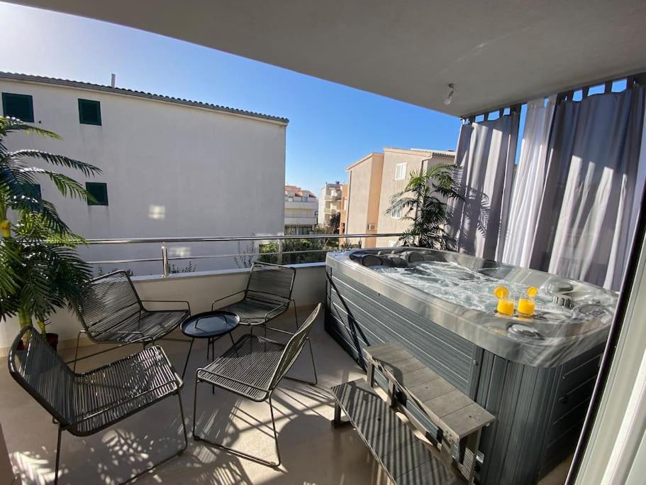 einen Balkon mit Stühlen und einem Whirlpool auf dem Balkon in der Unterkunft Luxury apartment with jacuzzi in Podstrana