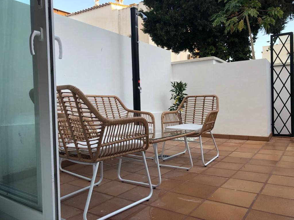 3 Rattanstühle und ein Tisch auf der Terrasse in der Unterkunft Suite PLAYAMAR con jacuzzi in Torremolinos