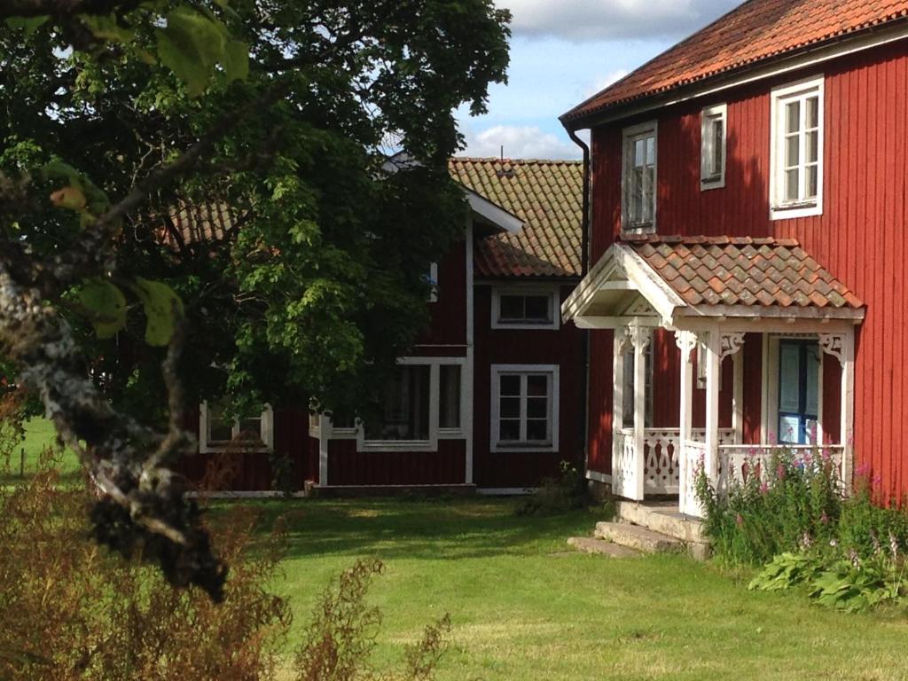 una casa rossa e bianca con una veranda bianca di Historisches großes Holzhaus von 1860, Familienferienhof Sörgården 1, Åsenhöga, Granstorp a Granstorp