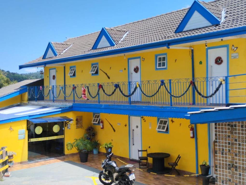 una casa amarilla con una motocicleta estacionada frente a ella en Pousada Cantinho da Mi & Teco, en Campos do Jordão