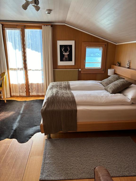 a bedroom with a large bed and windows at Alpina Boutique Hotel Ringgenberg in Ringgenberg