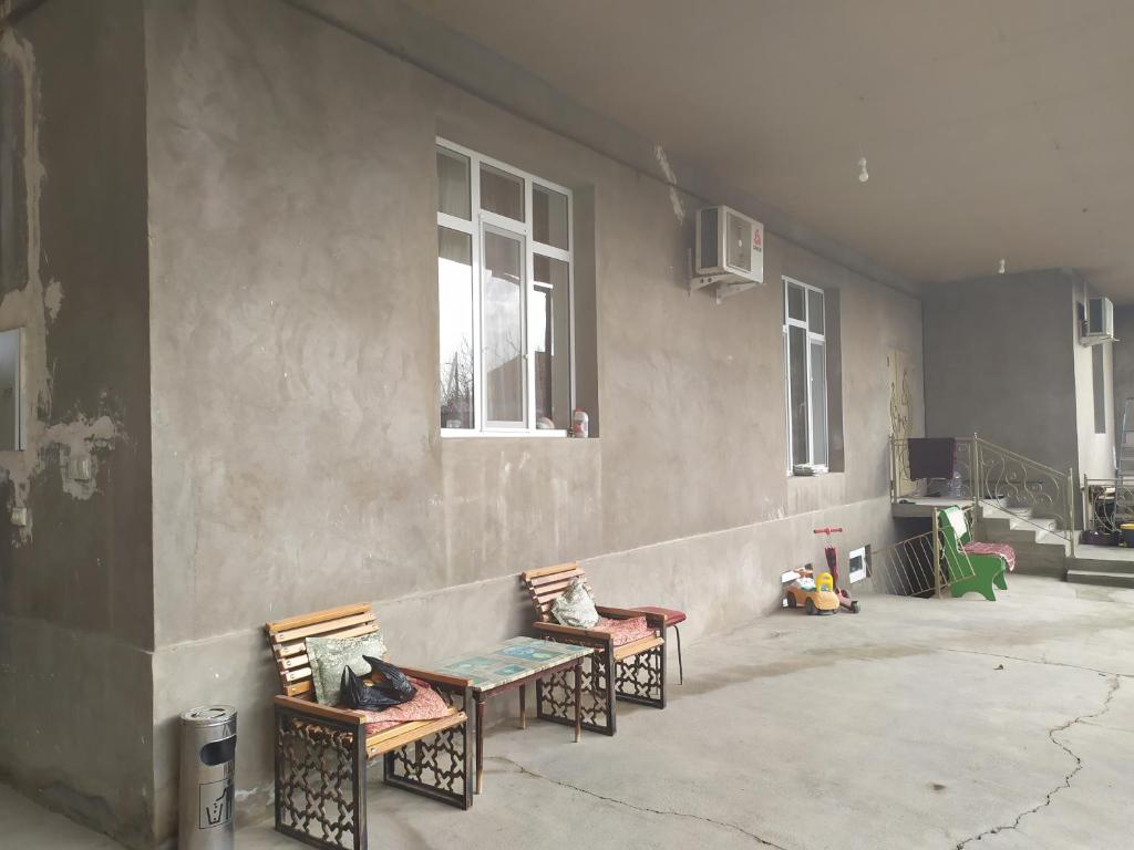 Habitación con 2 bancos y una pared con ventanas. en Дачный домик, en Tashkent