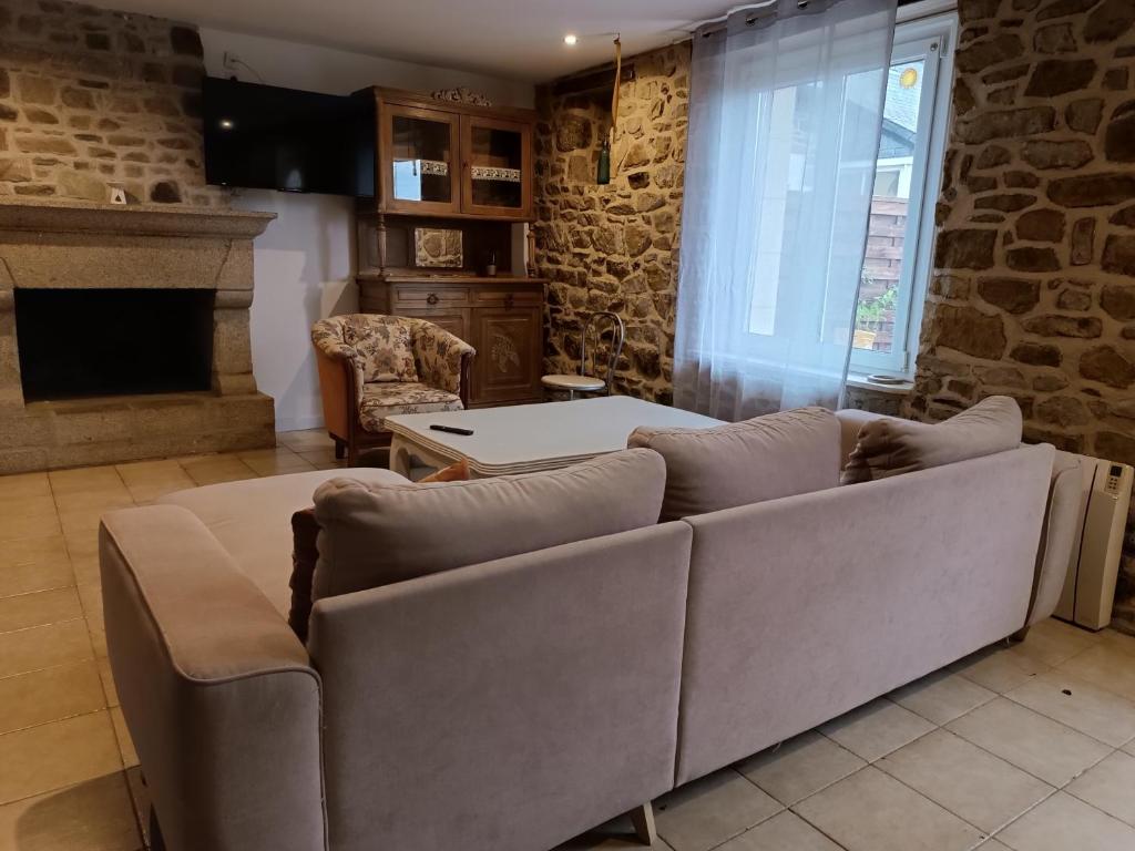 a living room with a couch and a stone wall at gite Conan in Plourivo