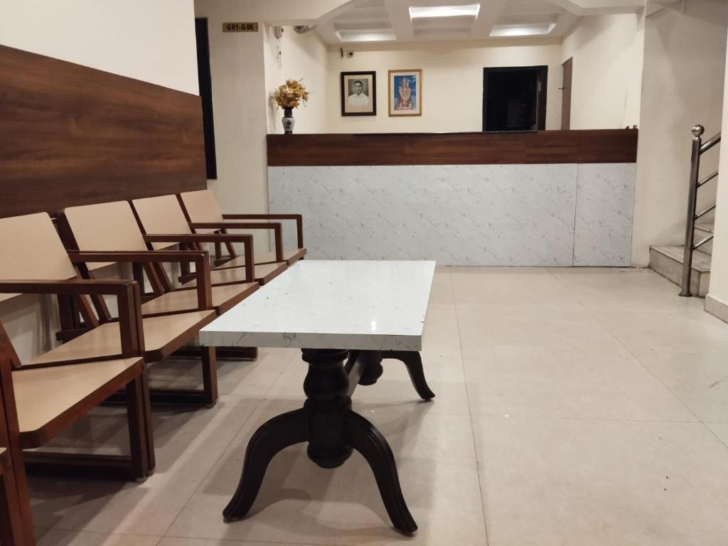 um quarto com cadeiras e uma mesa num quarto em Hotel Alankar em Kanyakumari