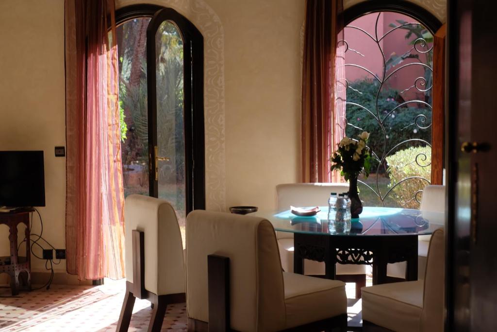 Eden Palm Resident Palmeraie Marrakech في مراكش: غرفة طعام مع طاولة وكراسي ونافذة