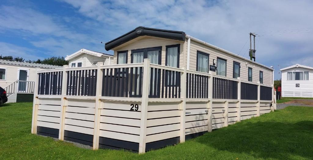 a house with a white fence in a yard at Bude Coastal Lodge in Bude