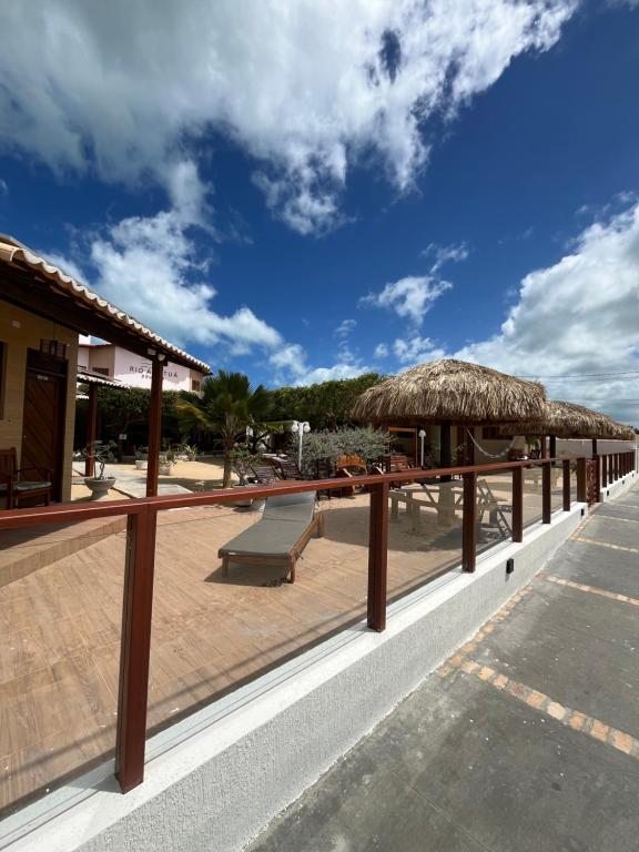 a deck with a bench and a straw umbrella at Pousada Rio Aratuá in Galinhos