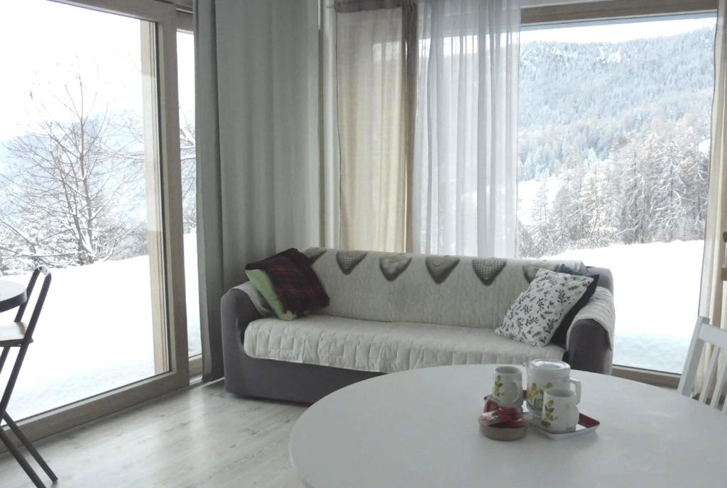 ein Wohnzimmer mit einem Sofa und einem Tisch in der Unterkunft B&B Tantané in Torgnon