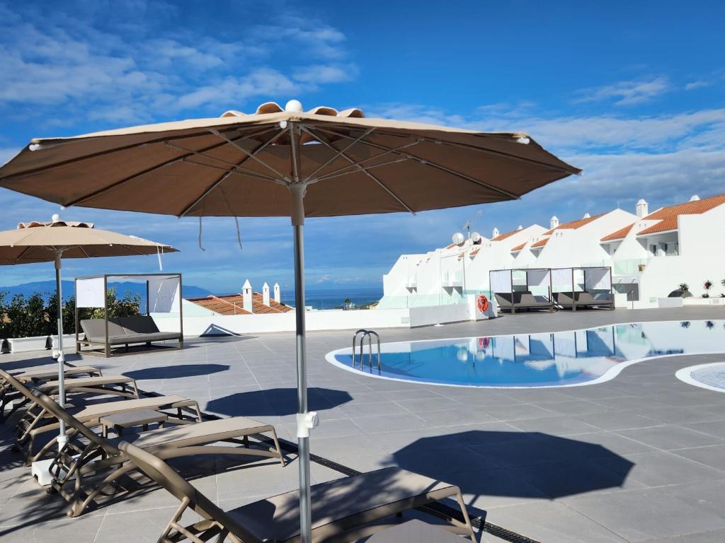 a patio with chairs and an umbrella next to a pool at Costa Adeje Garden Aparthotel in Adeje