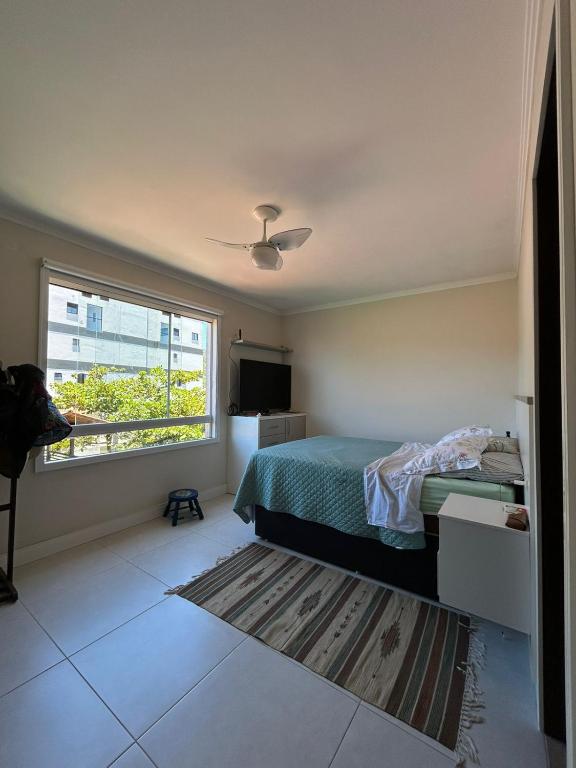 Schlafzimmer mit einem Bett und einem Fenster in der Unterkunft Suíte privativa - Praia do Canto Grande, Bombinhas in Bombinhas