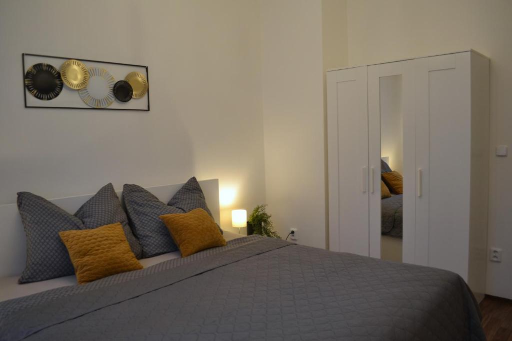 - une chambre avec un lit gris et des oreillers jaunes dans l'établissement Apartmán u Fontány, à Poděbrady