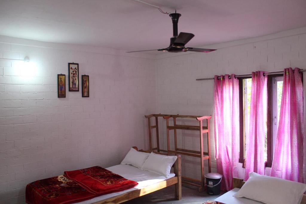 1 dormitorio con litera y cortinas rosas en Changmai's Inn kaziranga, en Kāziranga