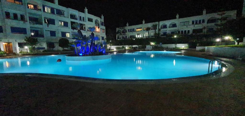 una gran piscina azul frente a un edificio por la noche en Kabila plage z6 appartement vue directe sur la piscine, en Sania Torres