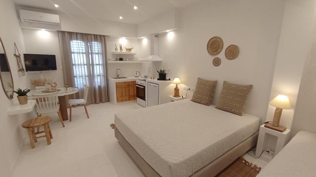 een witte slaapkamer met een bed en een keuken bij Evdion Naxos Town in Naxos Chora