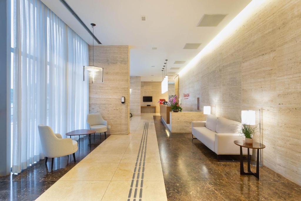 a hospital lobby with a white couch and chairs at Ramada by Wyndham Brasilia Alvorada in Brasilia