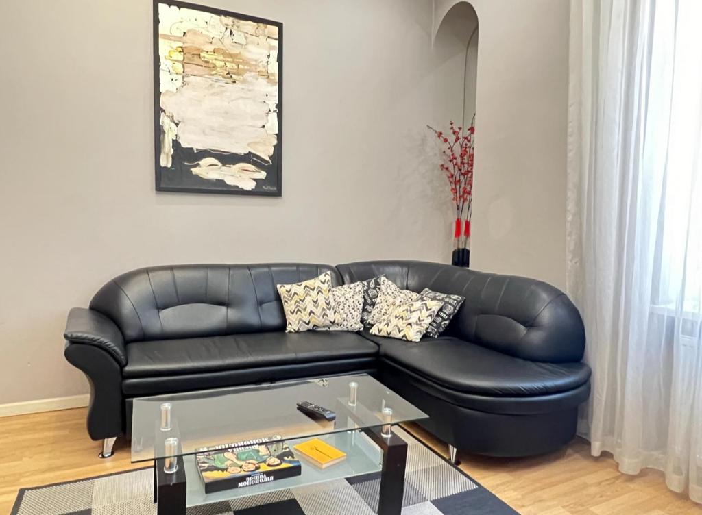 un divano in pelle nera in soggiorno con tavolo di Apartment Lesya Kurbasa a Lviv