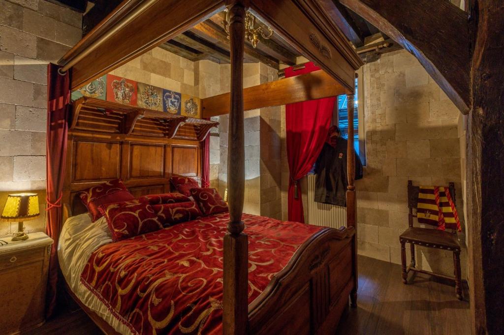 - une chambre avec un lit à baldaquin et une couette rouge dans l'établissement Appartement du Sorcier Magique expérience & Parking, à Dijon