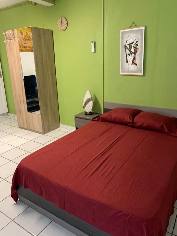 1 dormitorio con 1 cama grande con colcha roja en Logement avec parking à proximité de l’aéroport en Les Abymes