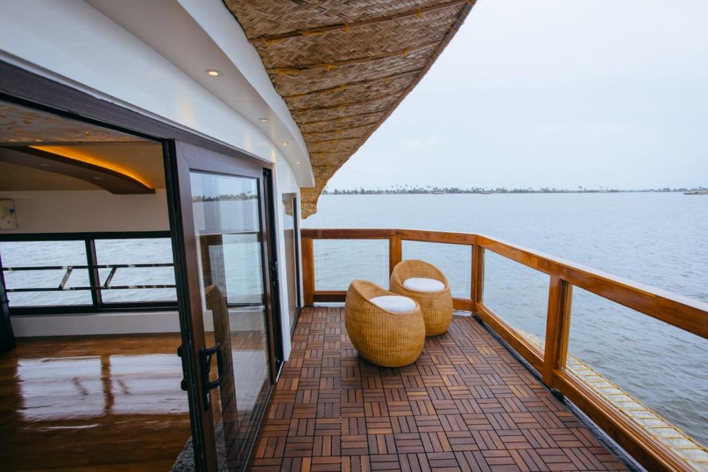 a balcony with two seats on a boat at Double Decker Houseboat in Alleppey