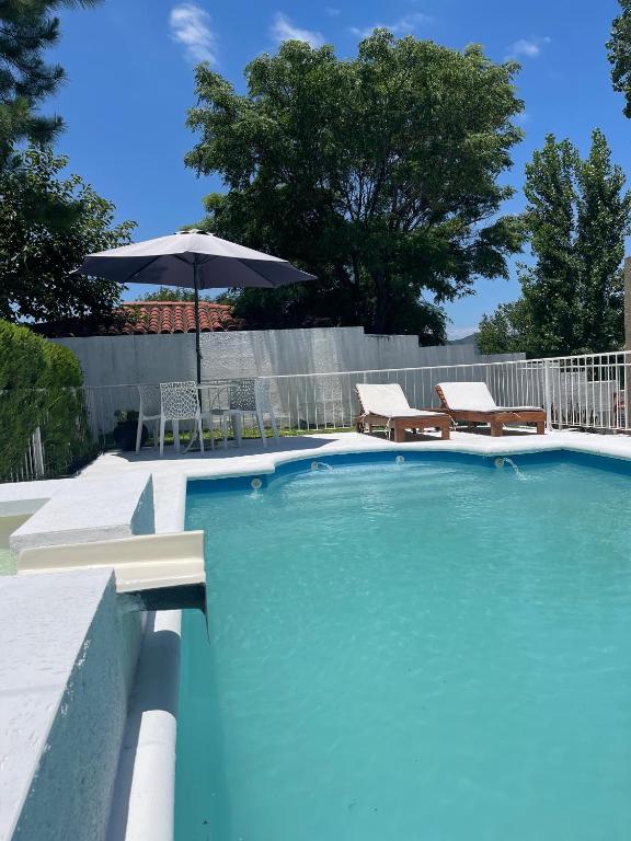 uma piscina com um guarda-sol e cadeiras e uma mesa em Brisas del Sur em Villa Carlos Paz