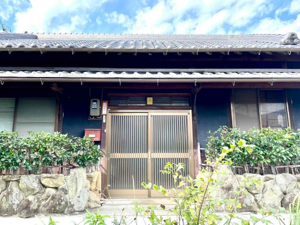 una casa blu con una porta in legno e alcune piante di ギャラリー宿　INNAHOUSE ANDAGALLERY a Murotsu