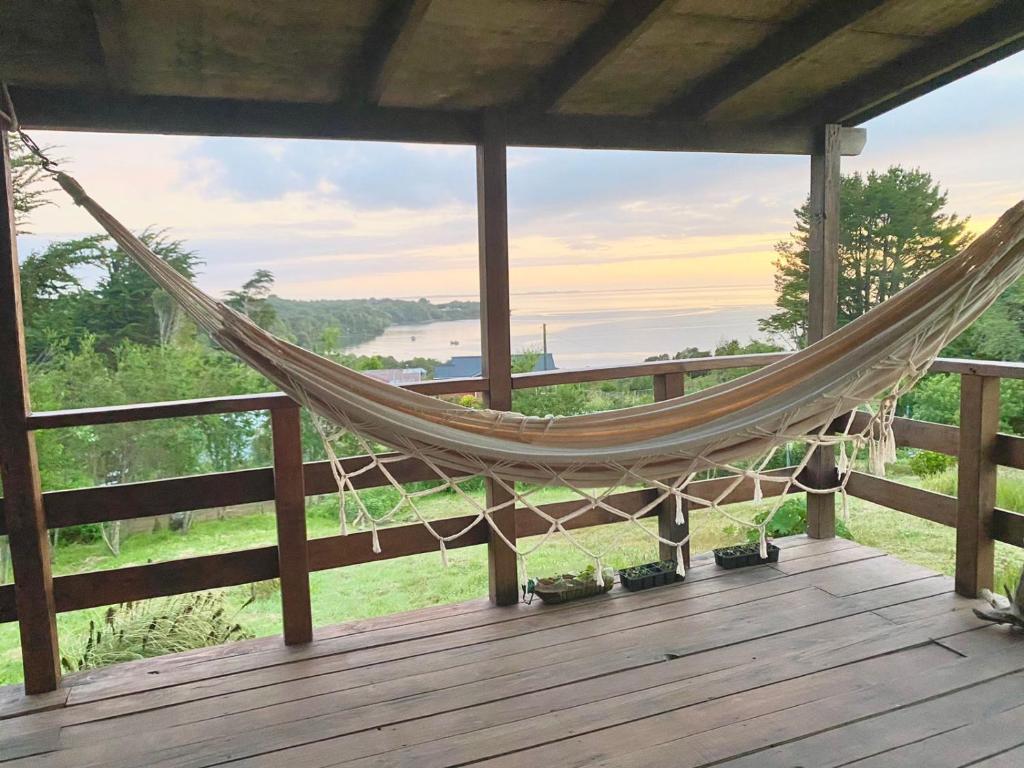 a hammock on a deck with a view at CASA PLAYA CHAICURA in Ancud