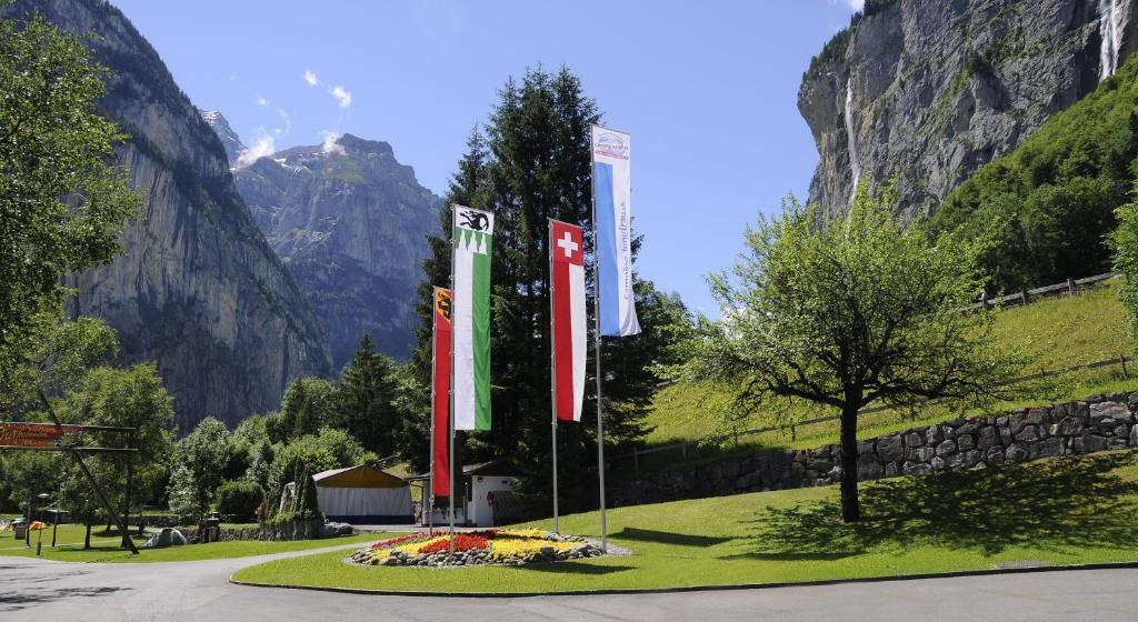 three flags in a field with mountains in the background at Camping Jungfrau in Lauterbrunnen