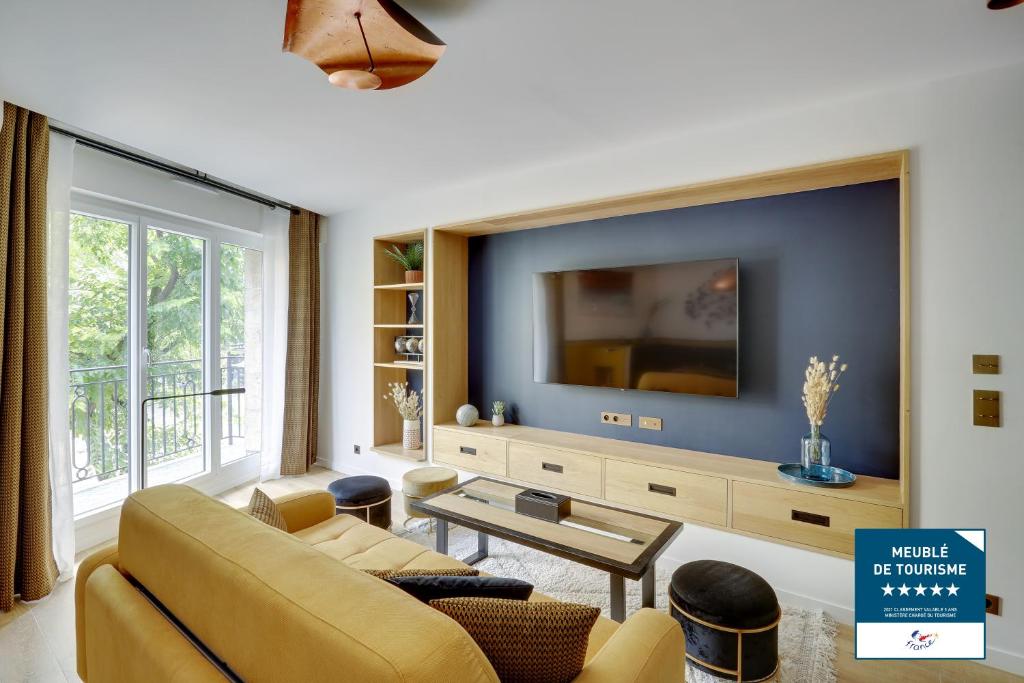 Una sala de estar con un sofá y un televisor. en Séjours Parisiens / Suite Étoile / 5*, en París