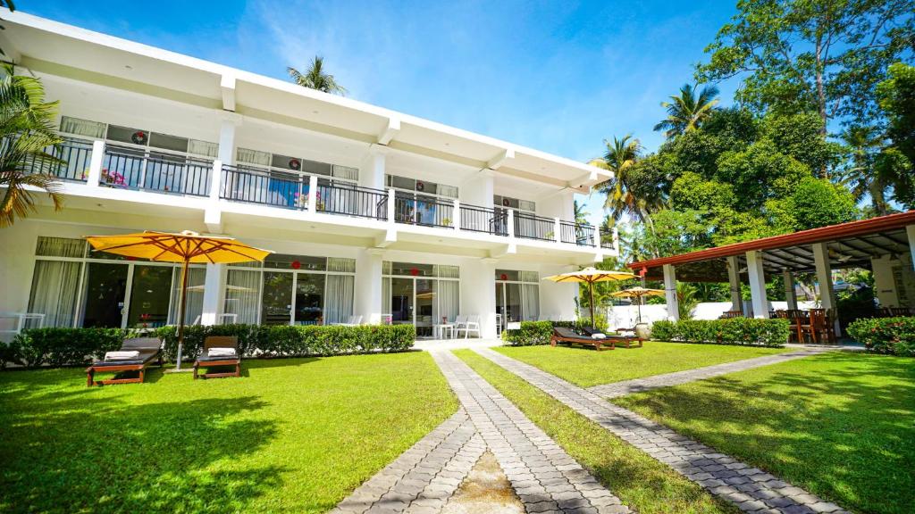 a large white building with chairs and an umbrella at Weleges Place in Hikkaduwa