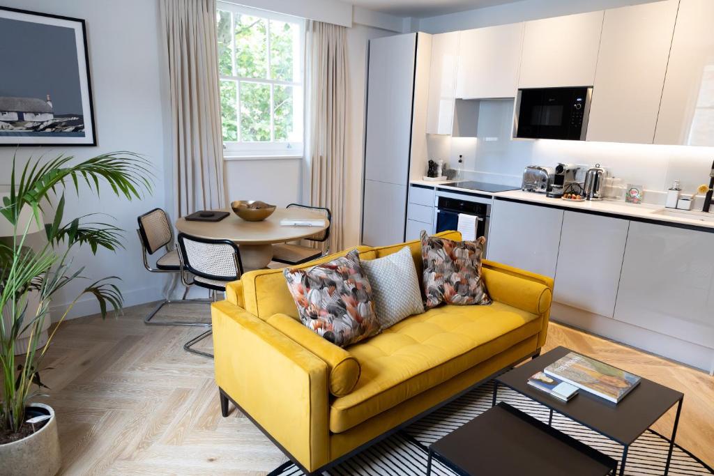 a living room with a yellow couch and a kitchen at Modern newly refurbished 2nd floor stylish flat in Fitzrovia in London
