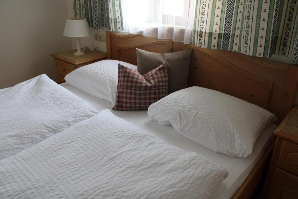 ein Bett mit weißer Bettwäsche und Kissen darauf in der Unterkunft Neufangbauer, Familie Sabine und Peter Hauser in Dorfgastein