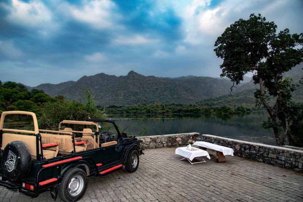 an old car parked next to a body of water at Shivika Lake Hotel Ranakpur in Sādri