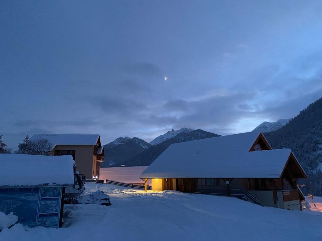 ein schneebedecktes Haus mit Bergen im Hintergrund in der Unterkunft Le Chalet des Sommets in Arvieux