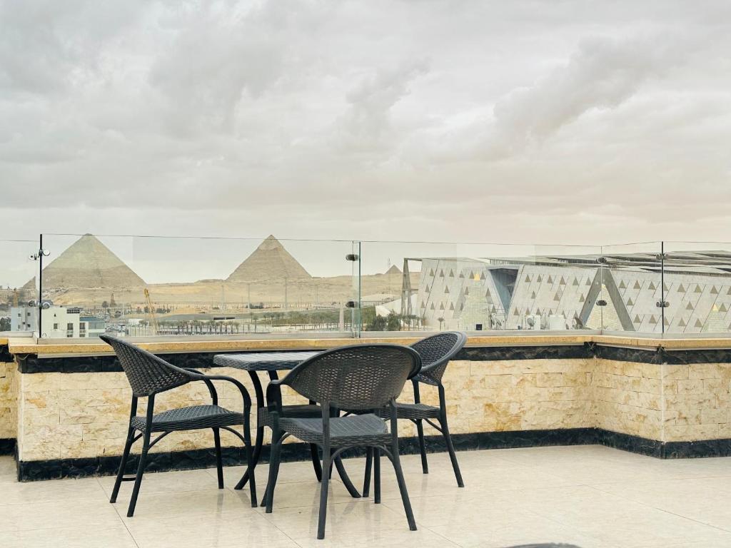 Jewel Grand Museum & Pyramids View في Giza: طاولة وكراسي على سطح مع الاهرامات