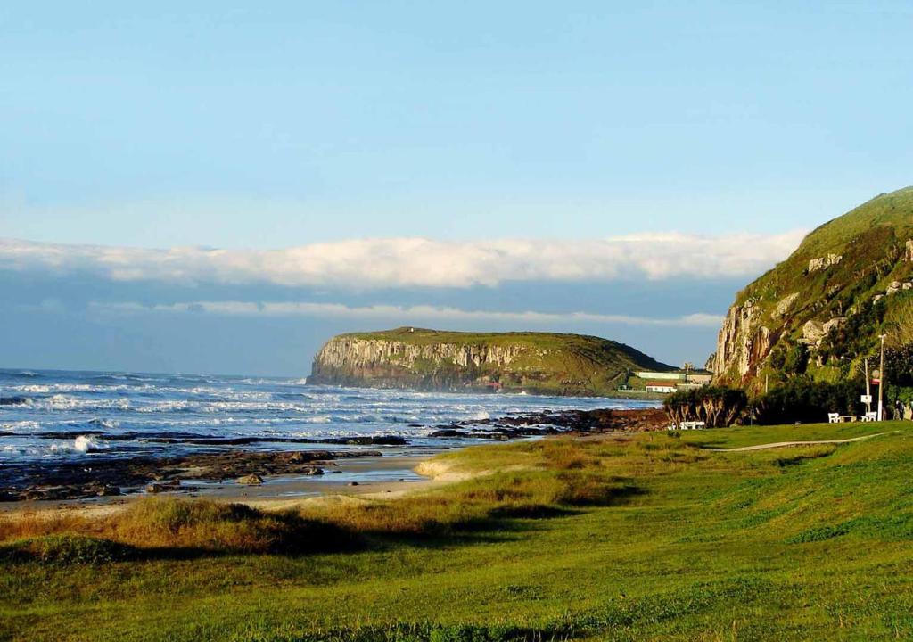 a view of the ocean with a large rock formation at Pousada House Sol & Praia in Torres