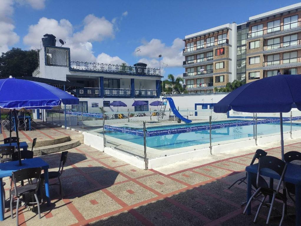 una piscina con sombrillas azules y un tobogán en Hotel Marqués de San Luis, en Melgar