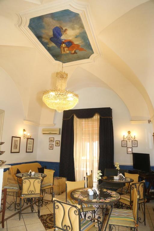a living room with tables and chairs and a chandelier at Hotel Sangiuliano 132 centro storico Catania in Catania