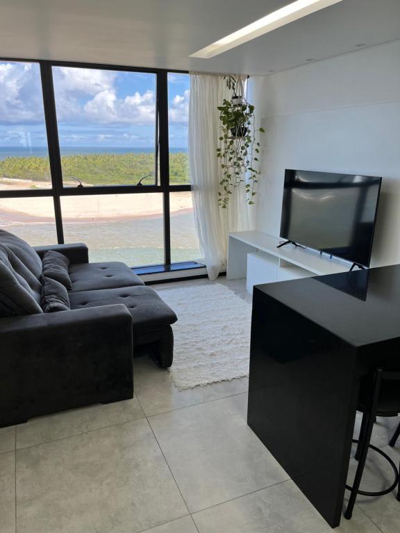 sala de estar con sofá negro y TV en Barra Home Stay - Beira mar - 2 QUARTOS, en Recife