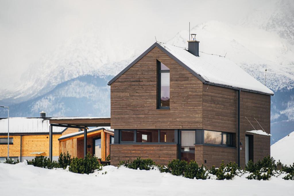 a house in the snow with mountains in the background at Domček Natur, Natur Resort in Veľká Lomnica