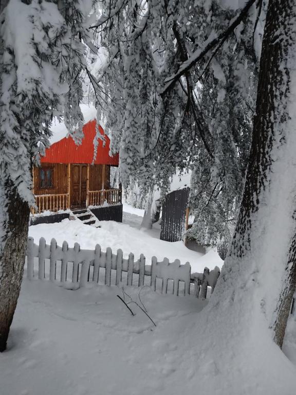 uma cerca na neve com um celeiro vermelho em Barybari em Khulo