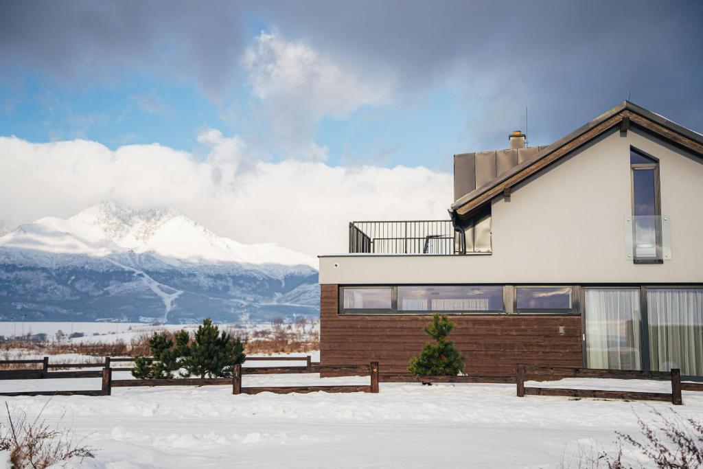 a house in the snow with mountains in the background at Naturia chata, NATUR RESORT in Veľká Lomnica
