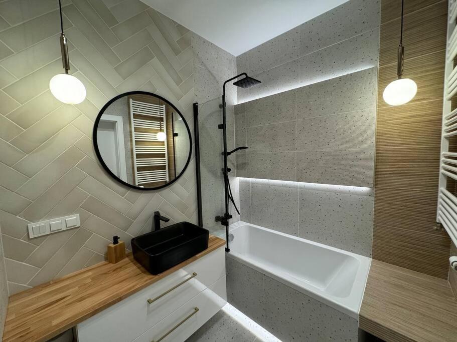 uma casa de banho com um lavatório, um espelho e uma banheira em Forest Apart IV em Varsóvia