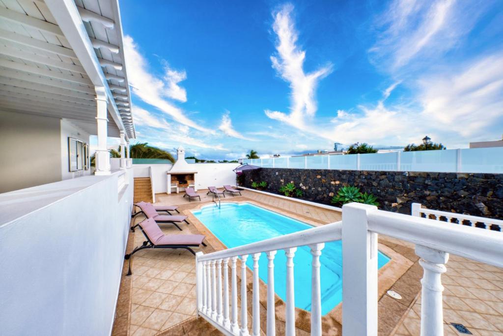a balcony with a swimming pool and patio furniture at Mar Azul Puerto Calero in Puerto Calero