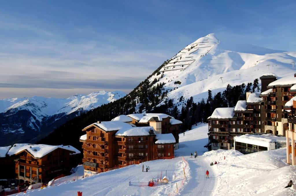 einen schneebedeckten Berg mit einer Skihütte an einer Skipiste in der Unterkunft Résidence Odalys La Licorne in La Plagne