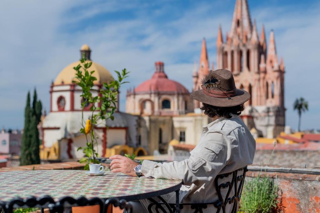 a woman sitting at a table with a cup of coffee at Suite de Lujo con Terraza Panorámica in San Miguel de Allende