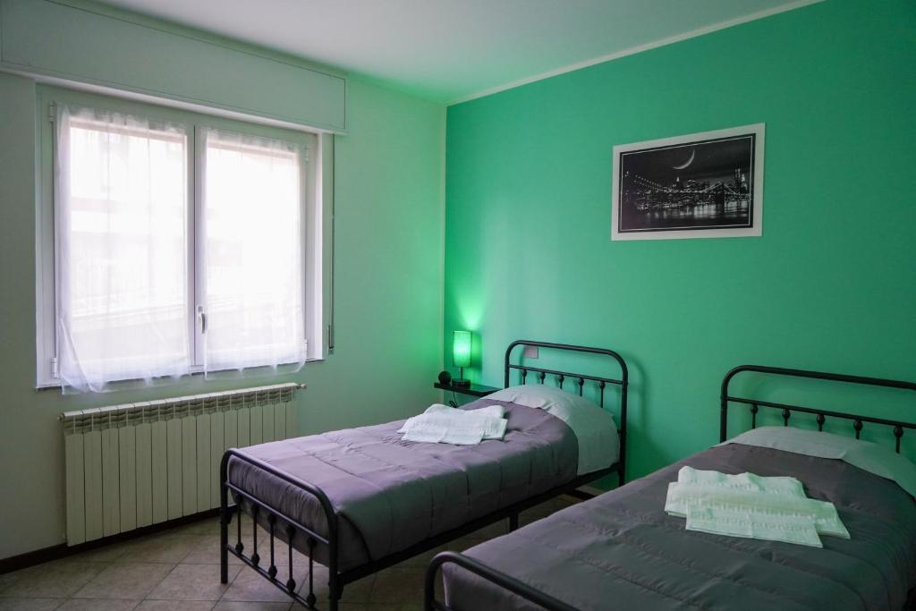 Habitación verde con 2 camas y ventana en A Home away From Home By Alex Appartamento Malpensa Prestige Residence en Busto Arsizio