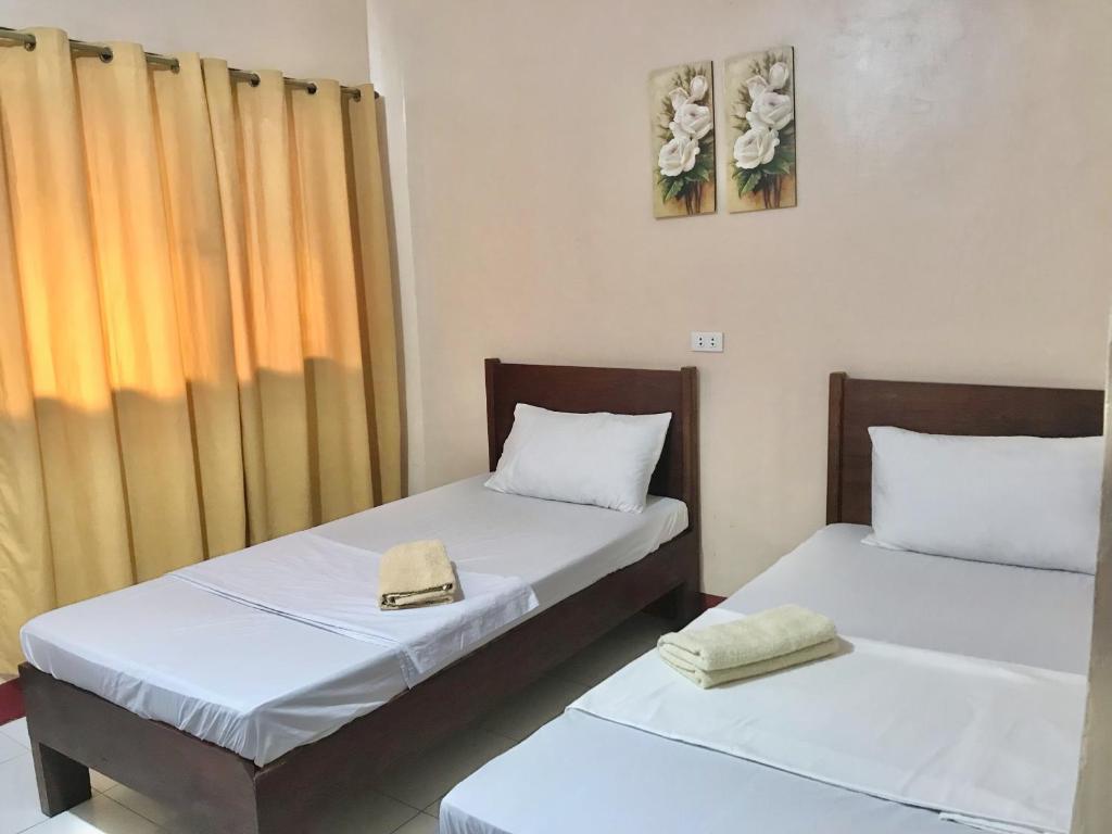 two beds sitting next to each other in a room at JBR Tourist Inn - Port Barton in Itaytay