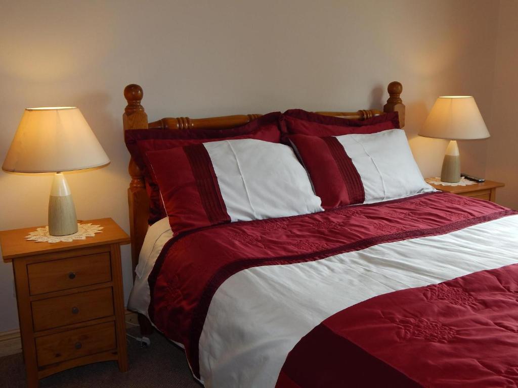a bedroom with a red and white bed with two lamps at Glencove in Ennis